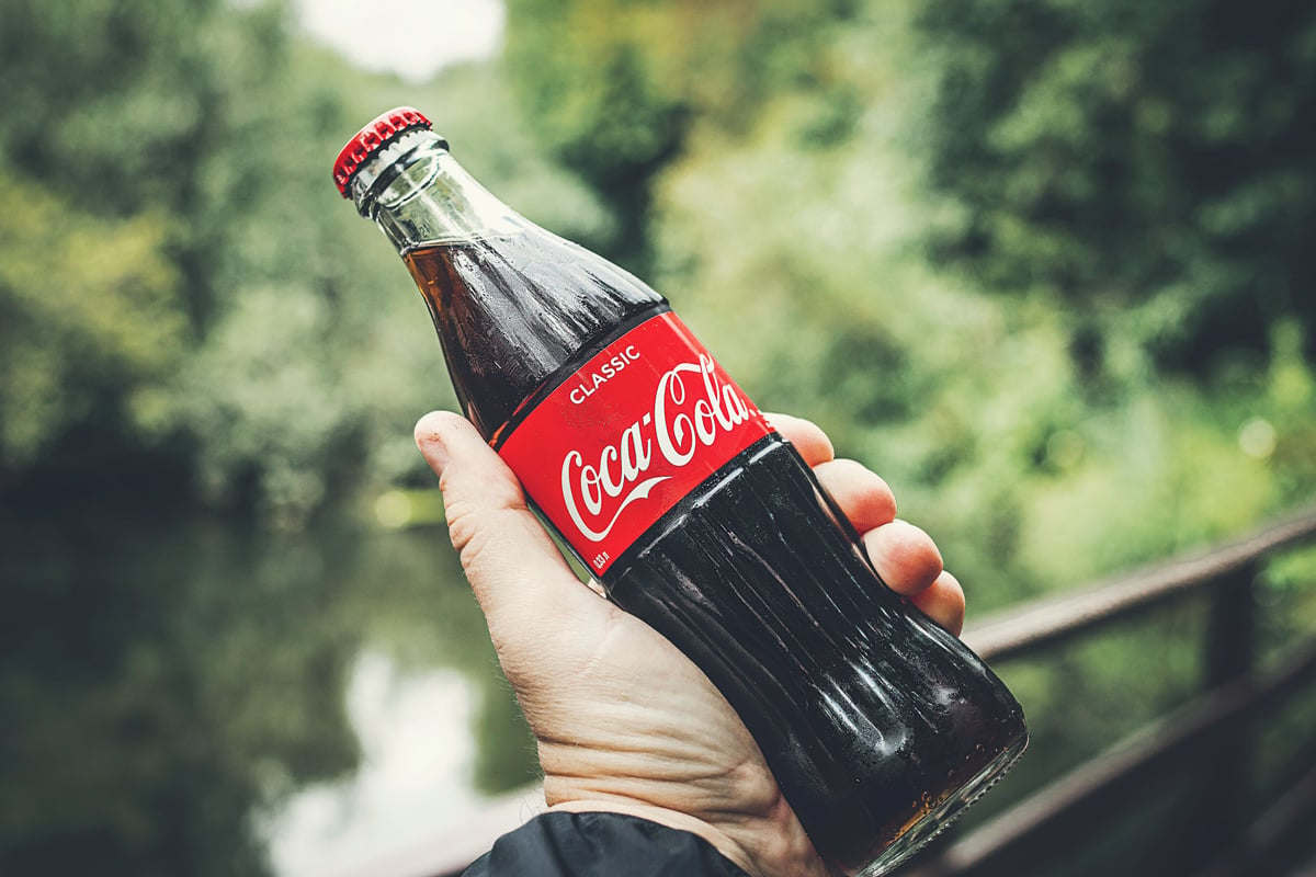 Selective Focus Photography of Person Holding a Coca-cola Bottle